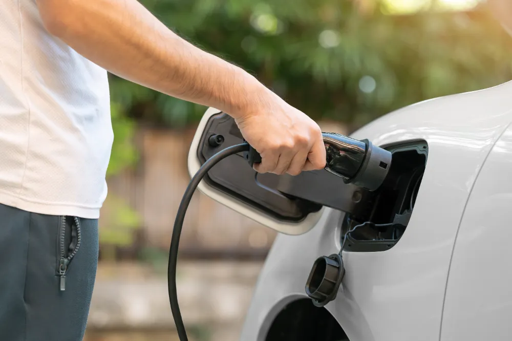 Sparks NV EV charger installation — close-up of a technician’s hands plugging a charging connector into a white electric vehicle, used in the Sparks service page hero/section image.