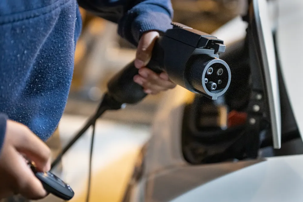 Close-up of a technician plugging an EV charger connector into a vehicle at a Sparks NV home