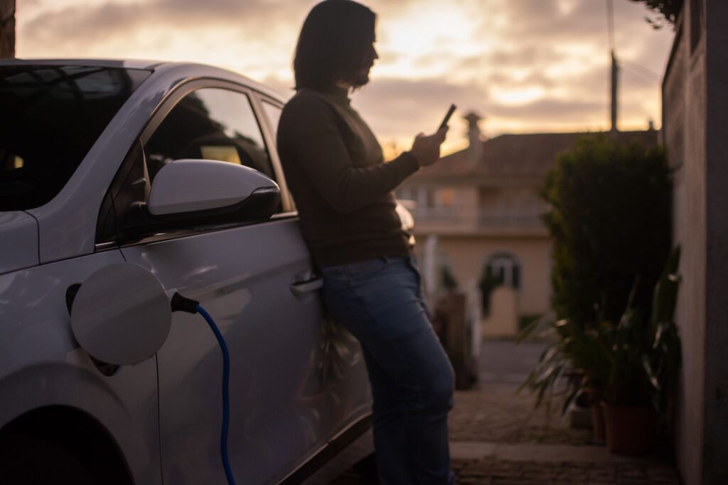 Electrician installing an outdoor EV charger station beside a home entryway.  