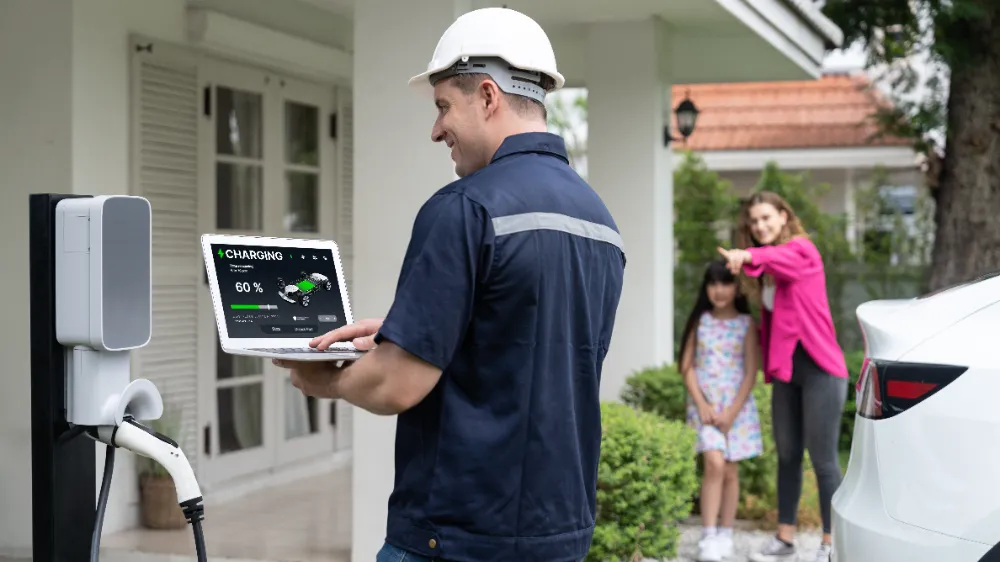 Electrician testing a home EV charger with a laptop while a family stands nearby outside their Incline Village home.  