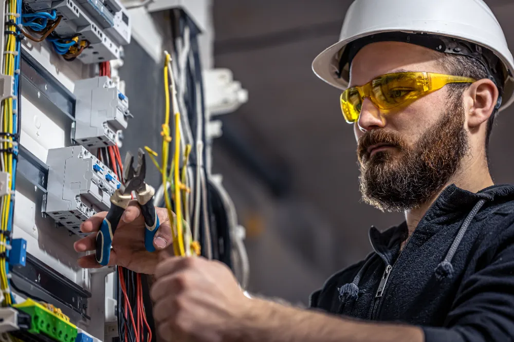 Licensed electrician working on an electrical panel installation during an active construction project